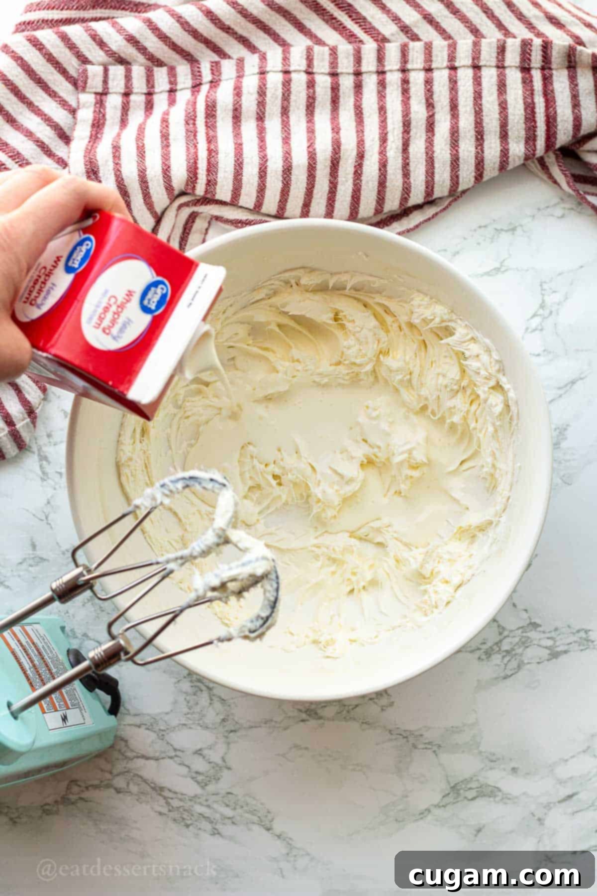 Strawberry Cheesecake Ice Cream (Easy Homemade Recipe) 5 Pouring cream into whipped cream cheese in bowl.