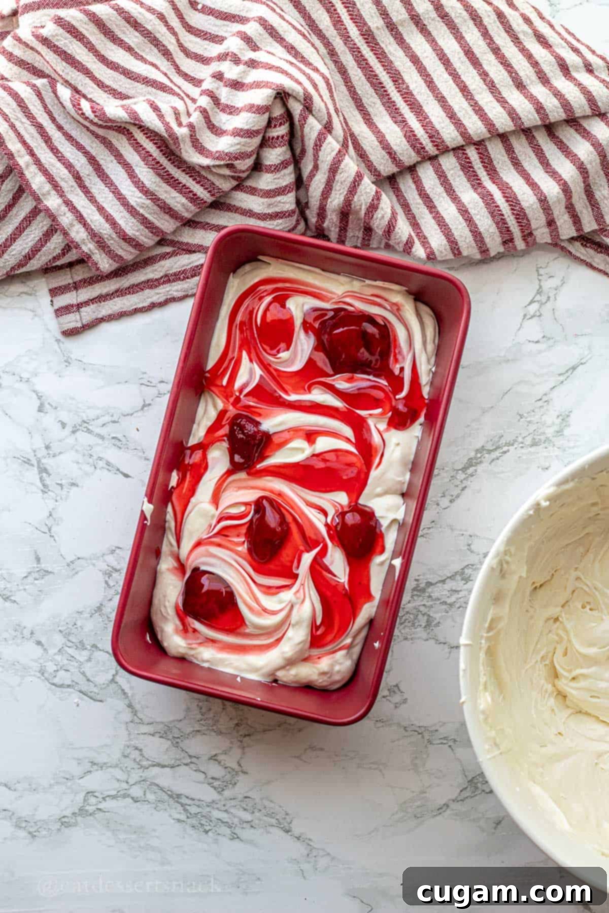 Strawberry Cheesecake Ice Cream (Easy Homemade Recipe) 7 Swirling strawberry pie filling in a pan of cream.