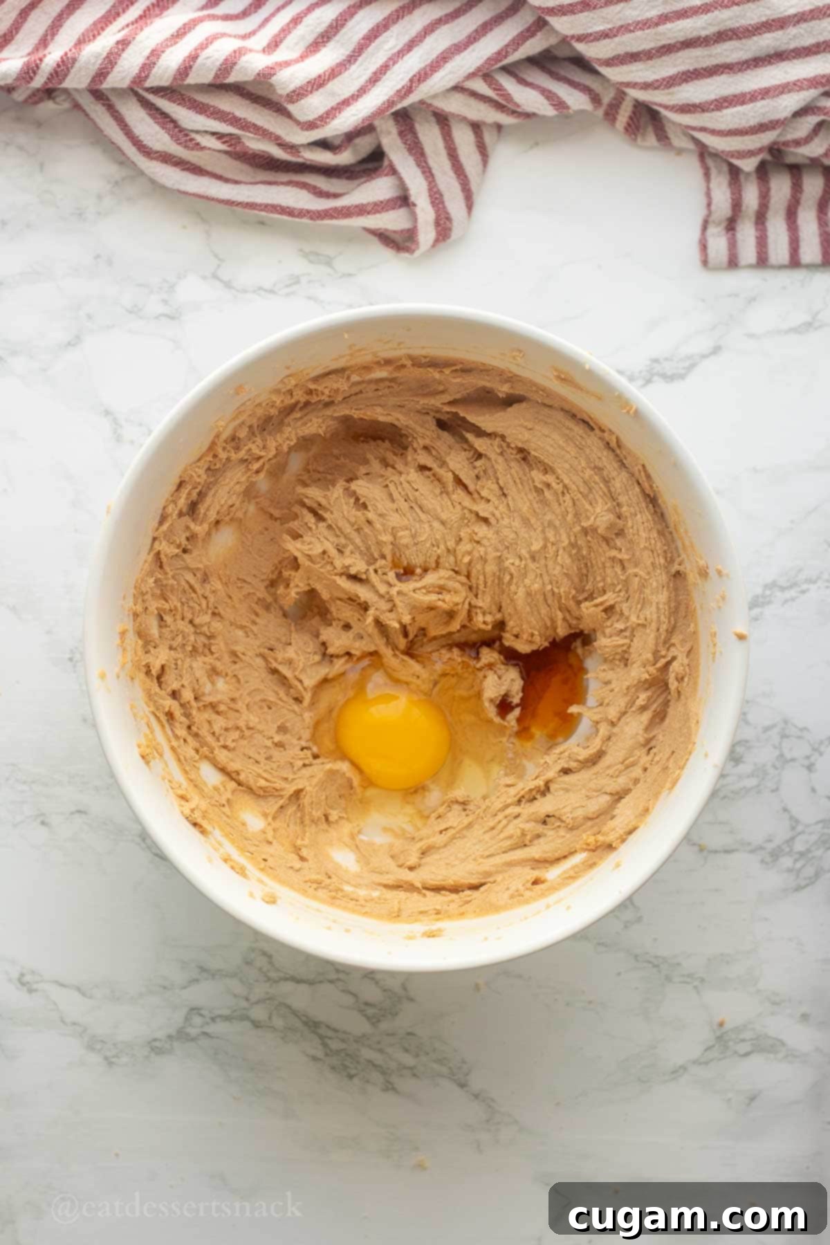 Chocolate Chip Peanut Butter Swirl Cookies 5 An egg and vanilla extract being added to the sugar and butter mixture in a mixing bowl.